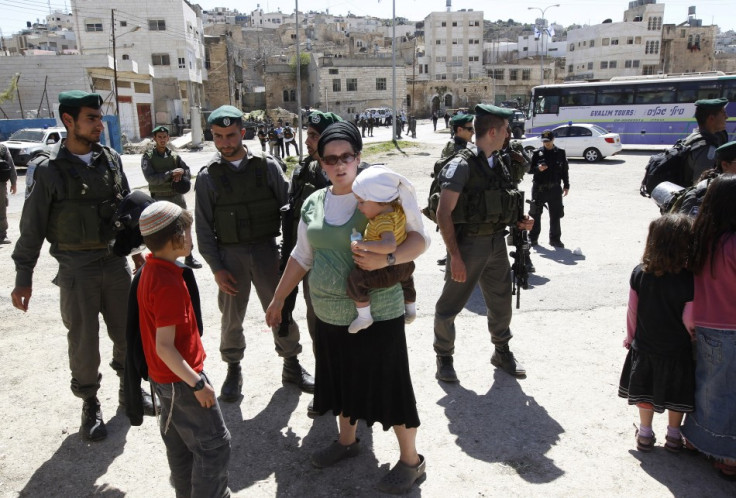 A Jewish settler stands near Israeli border policemen as they prevent her from reaching a building,