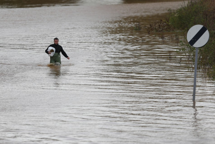 A man wades up a flooded street after rescuing items from his home (Reuters)