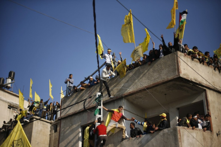 Palestinians stand atop a building as they take part in a rally marking the 48th anniversary of the founding of the Fatah movement, in Gaza City
