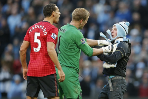 Manchester City's Joe Hart blocks Matthew Stott from reaching Manchester United's Rio Ferdinand after the latter was struck by an object thrown from the crowd (Reuters)