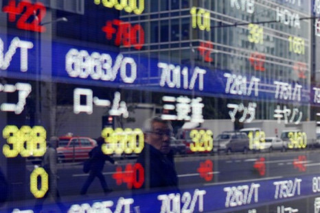 A man is reflected on a stock quotation board showing Japanese companies' stock prices outside a brokerage in Tokyo