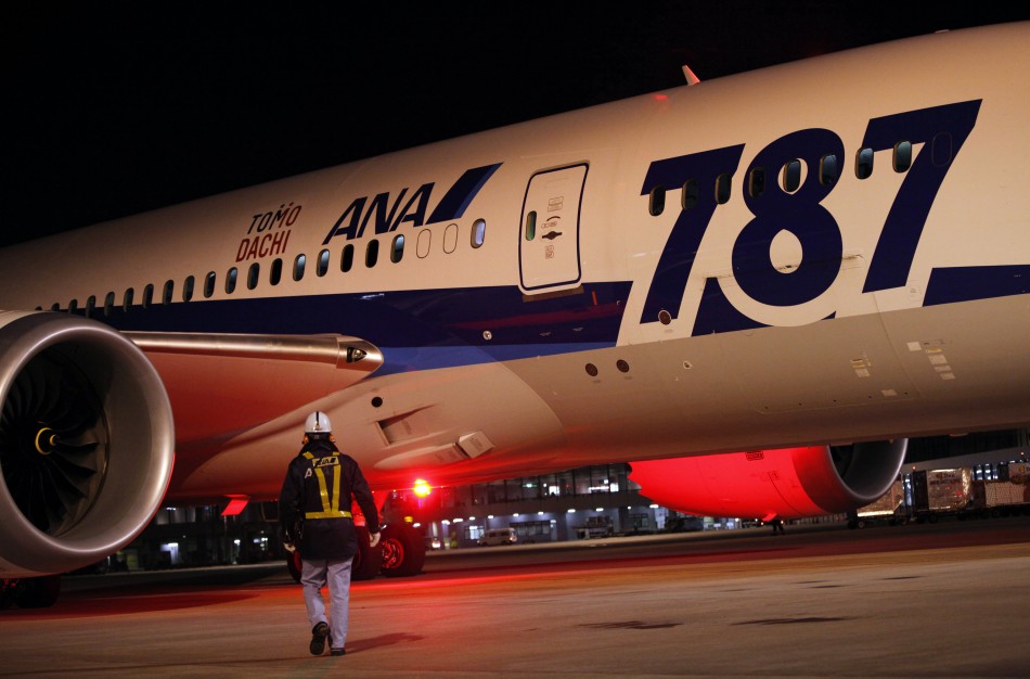 A man walks by a Boeing 787 Dreamliner on a runway.