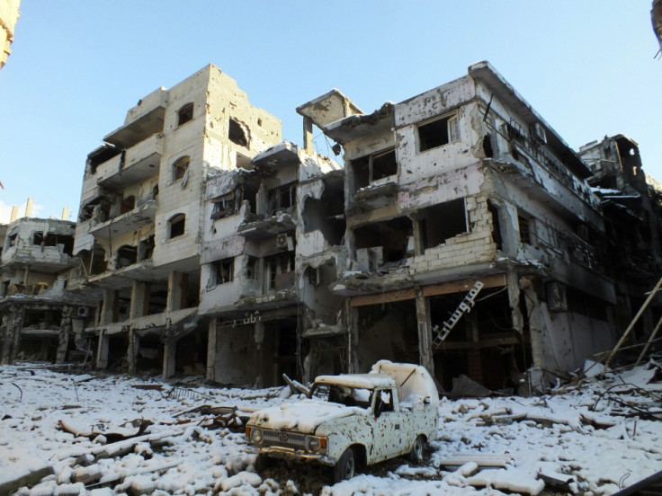 A damaged car and buildings covered with snow at Jouret al Shayah area in Homs