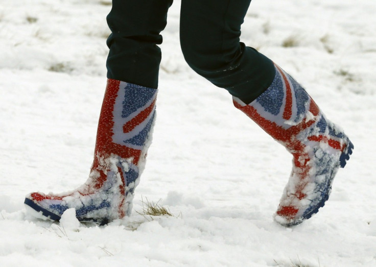 A woman walks through snow in Wellington boots printed with the Union flag in Newtown Linford