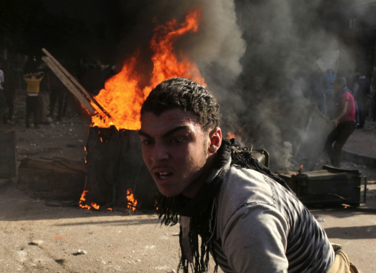 A protester is seen in front of fire set by protesters during clashes against riot police in Alexandria