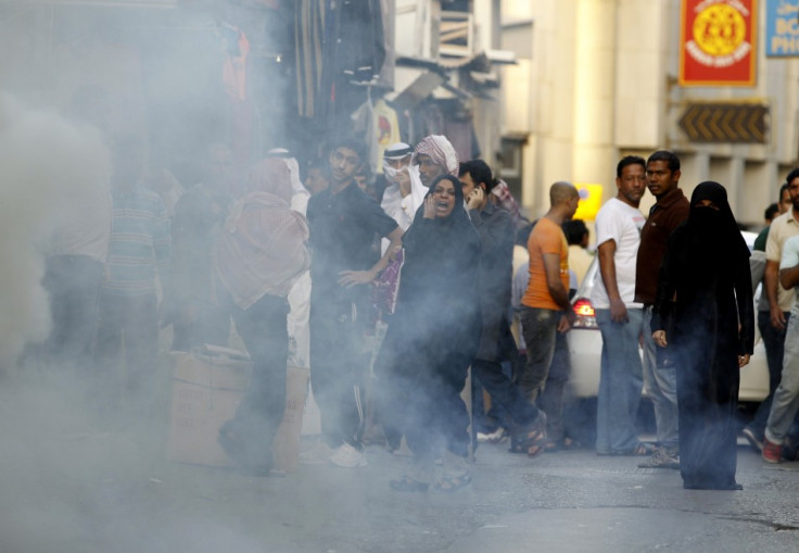 An anti-government protester shouts back at riot police as tear gas smoke is seen during a protest in Manama