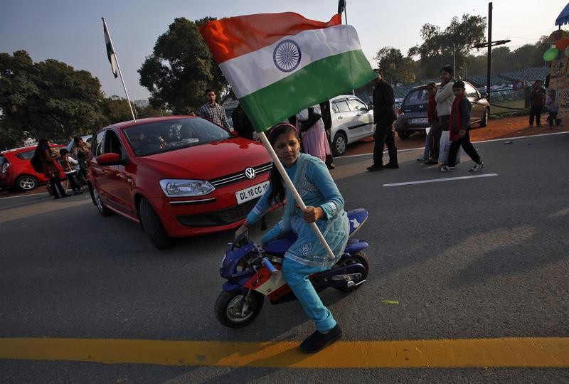 A woman waves Indias national flag as she rides her mini bike near the India Gate during the Republic Day celebrations in New Delhi January 26, 2013.