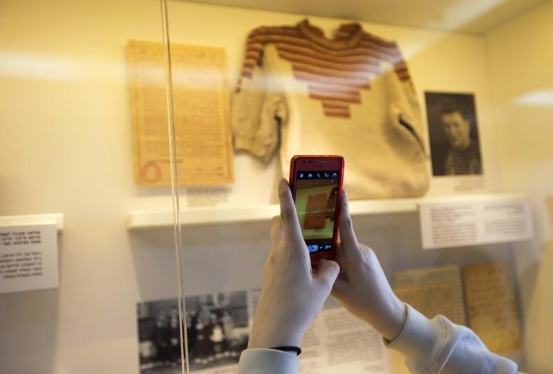 Grand-daughter of Holocaust survivor Gucia Teiblum, takes a photograph of a sweater knitted by her grandmother at a Nazi concentration camp, during the opening of a new display at the Yad Vashem Holocaust History Museum in Jerusalem January 27, 2013. quo