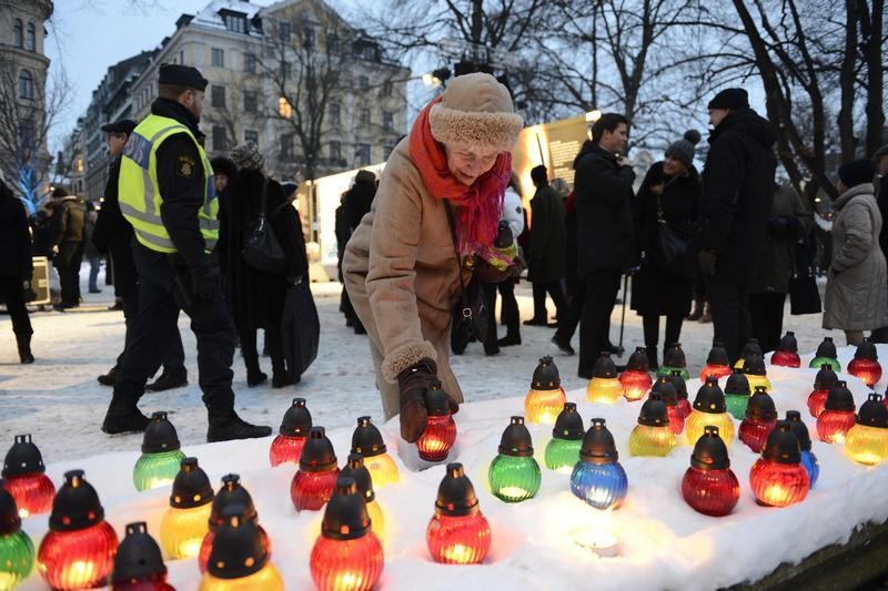 A woman lights a candle during a memorial ceremony for International Holocaust Remembrance Day at Raoul Wallenberg Square in Stockholm in this January 27, 2013 picture taken by Scanpix Sweden.
