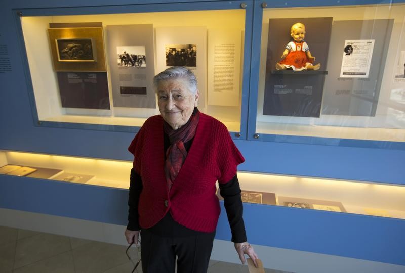Tzvia Shkolnik, a friend of late Holocaust survivor Edit Faber, poses for a photograph near a doll which had been hidden with Faber during World War Two, during the opening of a new display at the Yad Vashem Holocaust History Museum in Jerusalem January 2