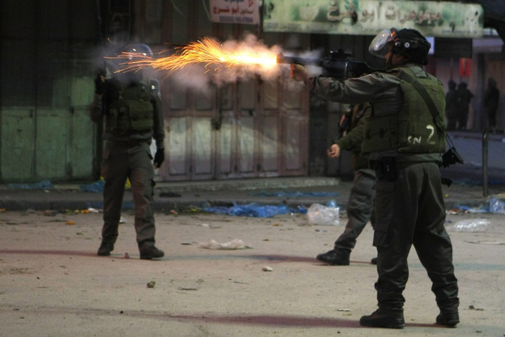 An Israeli security officer fires a tear gas