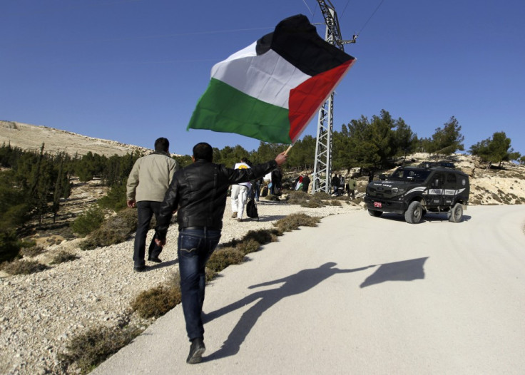 A Palestinian protester holds a flag as he arrives at an area known as "E1", which connects the two parts of the Israeli-occupied West Bank