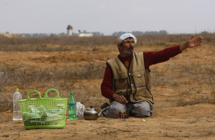 A Palestinian farmer gestures as an Israeli watchtower (rear) is seen near the fence between Israel and the southern Gaza Strip November 24, 2012.