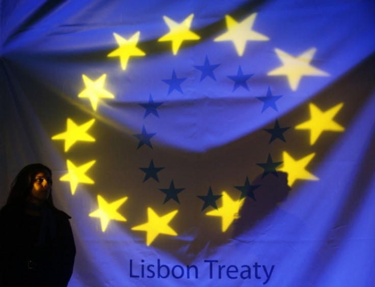 A woman stands in front of a banner displaying the stars of the European Union flag before a ceremony to mark the start of the European Union?s Lisbon reform treaty in Lisbon December 1, 2009.