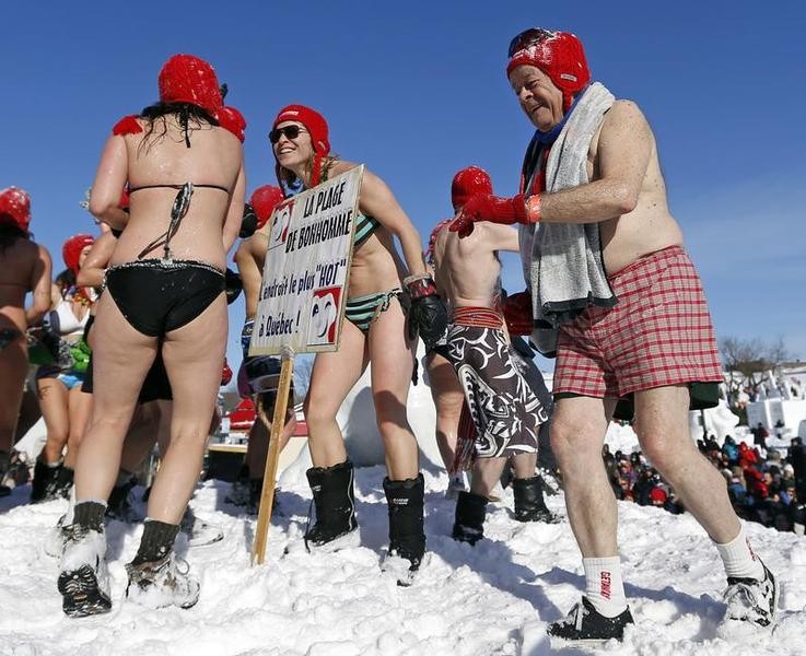 People play in the snow during the snow bath at the Quebec Winter Carnival on the Plains of Abraham in Quebec City, February 16, 2013. The sign reads Bonhommes beach, the hottest place in Quebec.