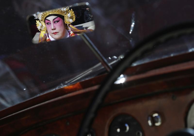 A woman dressed in traditional costume is reflected in the mirror of a 1956 Bentley as she takes part in the 14th Annual Chinatown Lunar New Year Parade in New York, February 17, 2013. This year celebrates the year of the snake in the Chinese calendar.