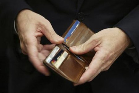 Treasury Secretary Geithner puts a piece of foreign currency back in his wallet during a break in his testimony on Capitol Hill in Washington