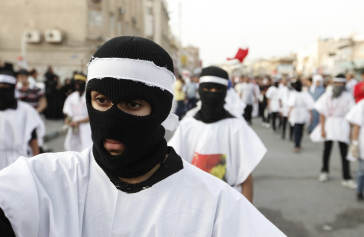 Protesters wearing burial shrouds take part in a procession during a visit to the grave of a 16-year-old youth killed by Bahraini security forces in clashes on February 14