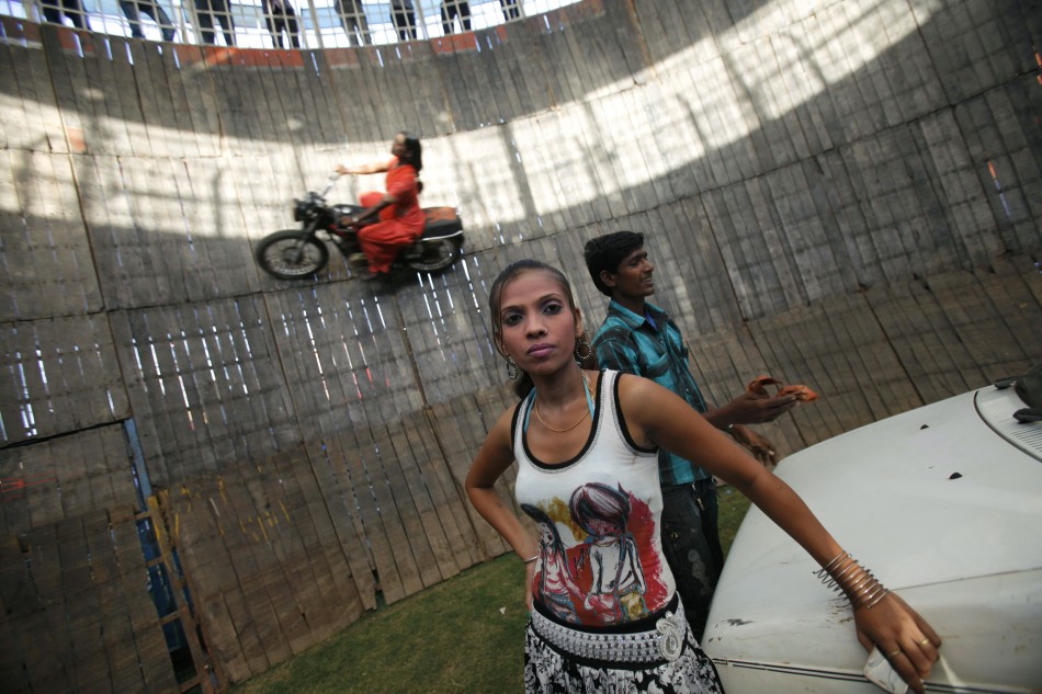 A team member front is seen as Salma Pathan, 21, a performer from the western Indian state of Maharashtra, performs a stunt as she rides a bike on the walls of the Well of Death, one of the attractions at Ramlila fair, in the old quarters of