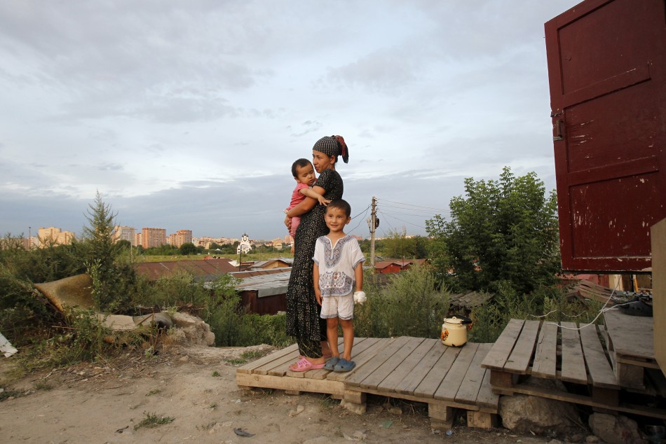 A migrant woman stands with her daughter and nephew outside their shelter on the outskirts of Moscow July 26 2011.