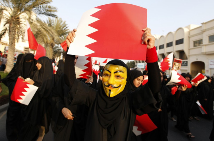 A female protester, wearing a Guy Fawkes mask, holds a Bahraini paper flag in an anti-government rally in Budaiya, west of Manama March 1, 2013.