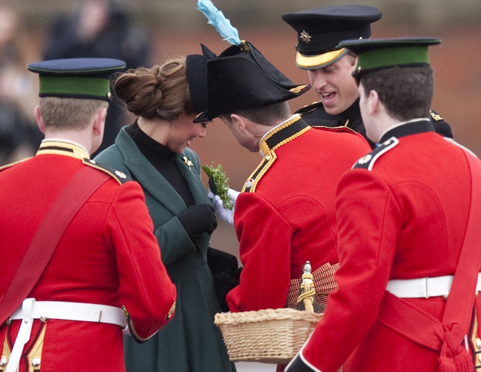 Britains Catherine, Duchess of Cambridge 2nd L is presented with a shamrock during a visit with her husband Prince William 2nd R to the 1st Battalion Irish Guards for a St Patricks Day Parade at Mons Barracks in Aldershot, southern England