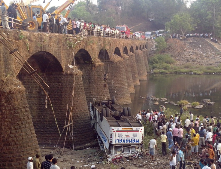 Rescuers and bystanders look at the wreckage of a passenger bus after it fell from a bridge in Ratnagiri district in the western Indian state of Maharashtra