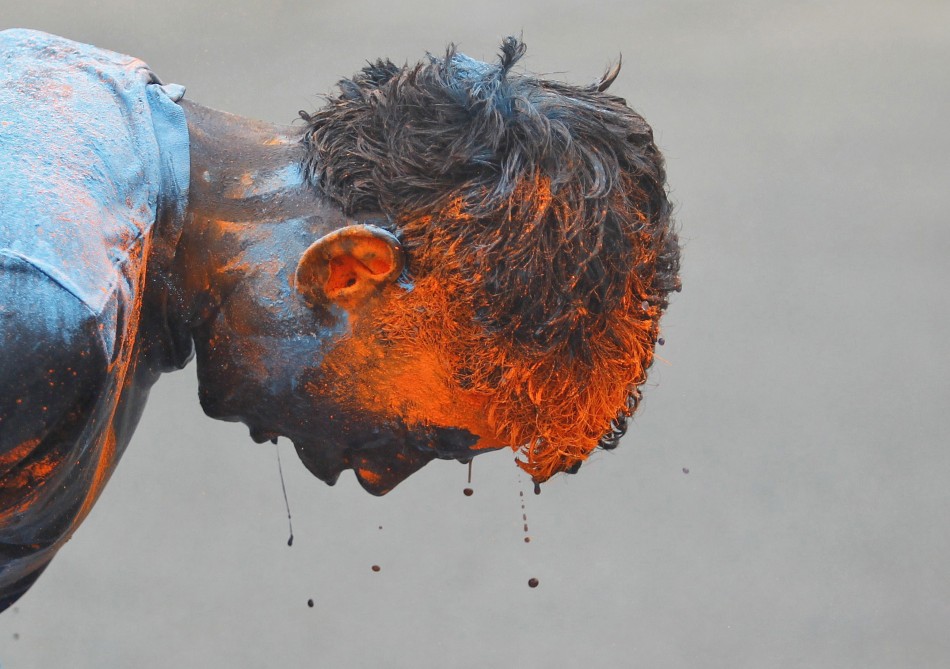 A schoolboy reacts after coloured powder was thrown on him by an another schoolboy during celebrations of Holi, also known as the festival of colours, outside their school in the western Indian city of Ahmedabad March 26, 2013. The traditional event heral