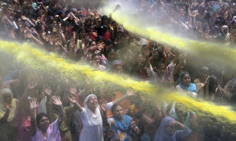 People raise their hands to receive coloured holy water from a priest during celebrations for Holi, also known as the festival of colours, in Jammu March 24, 2013. The traditional event heralds the beginning of spring and is celebrated all over India.