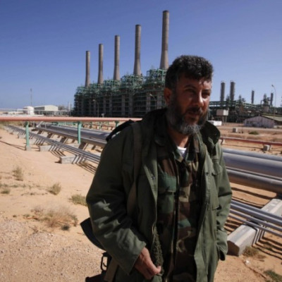 An armed National Transitional Council fighter patrols inside the Libyan Oil Refining Company in Ras Lanuf