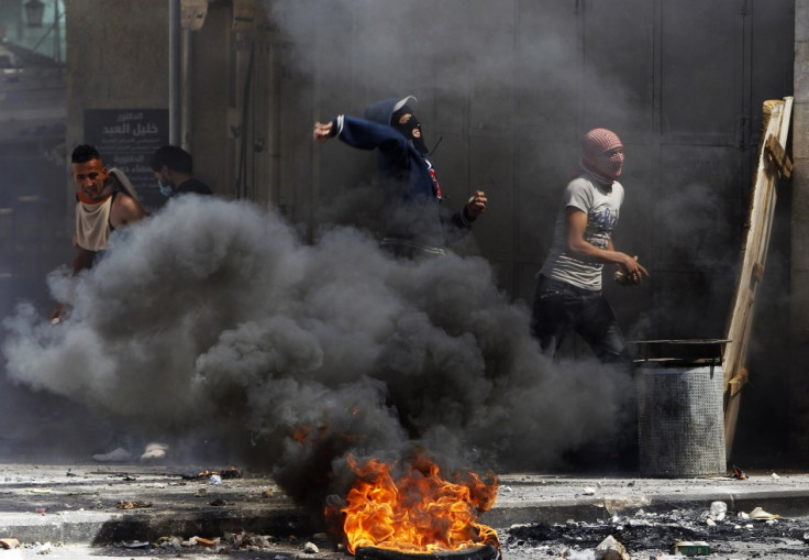 Palestinian protesters throw stones near a burning tyre during clashes with Israeli soldiers in the West Bank city of Hebron, after Maysara Abu Hamdeya