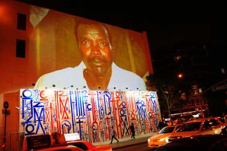 Passersby walk under a projection that is part of the non-profit organization Invisible Children's "Kony 2012" viral video campaign,