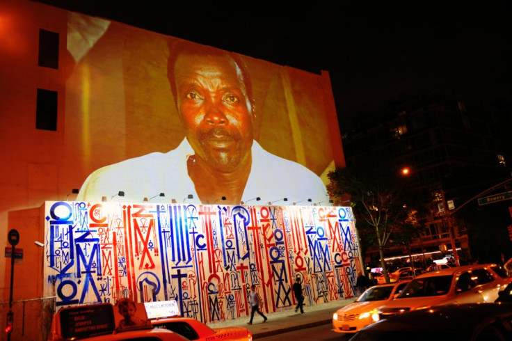 Passersby walk under a projection that is part of the non-profit organization Invisible Children's "Kony 2012" viral video campaign,