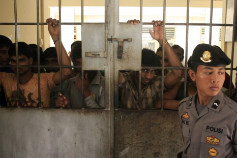 A police officer stands guard near migrants from Myanmar at an immigration detention centre in Medan in Indonesia's North Sumatra