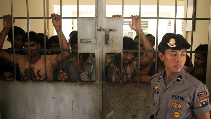 A police officer stands guard near migrants from Myanmar at an immigration detention centre in Medan in Indonesia's North Sumatra