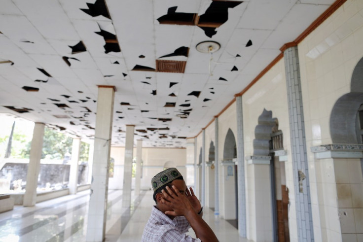 A Muslim man calls for prayers in a mosque damaged during recent violence in town of Minhla