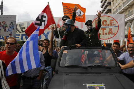 Demonstrators, dressed as Nazis, wave a Greek and a swastika flag as they ride in an open-top car in Syntagma Square in Athens as they protest against the visit of Germany's Chancellor Angela Merkel,