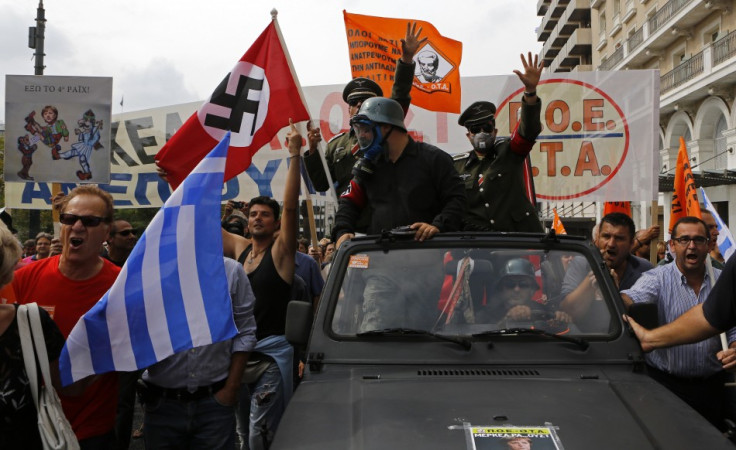 Demonstrators, dressed as Nazis, wave a Greek and a swastika flag as they ride in an open-top car in Syntagma Square in Athens as they protest against the visit of Germany's Chancellor Angela Merkel,