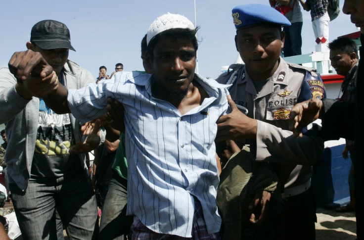 A police officer guides an ethnic Rohingya refugee from Myanmar off a boat