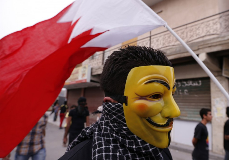 A protester, wearing a Guy Fawkes mask and with the Bahraini flag behind him, participates in an anti-government protest in the village of Diraz