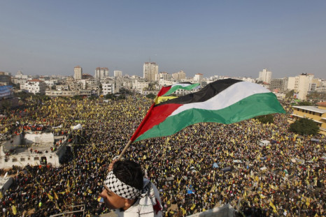 A boy waves a Palestinian flag during a rally marking the 48th anniversary of the founding of the Fatah movement,