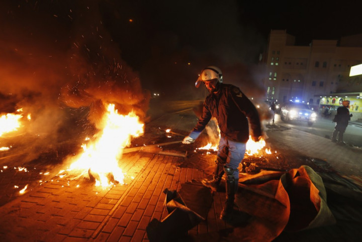 A riot police officer removes burning tyres from the highway set up by anti-government protesters in the village of Dira A riot police officer removes burning tyres from the highway set up by anti-government protesters in the village of Dira