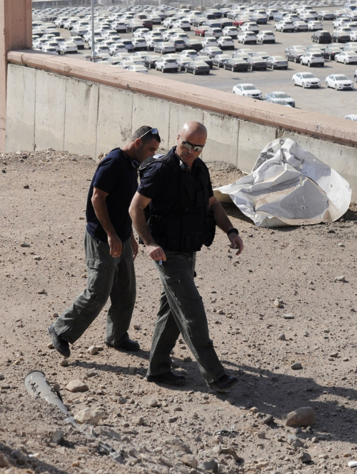 Israeli police explosives experts walk near a rocket which was fired into the Red Sea