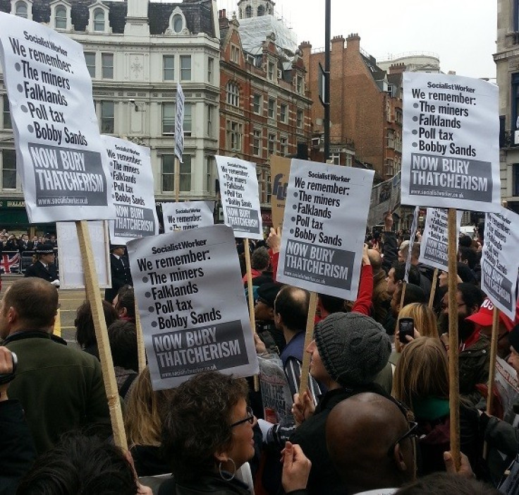 Protesters hold placards with anti-Thatcher statements during the day of her funeral
