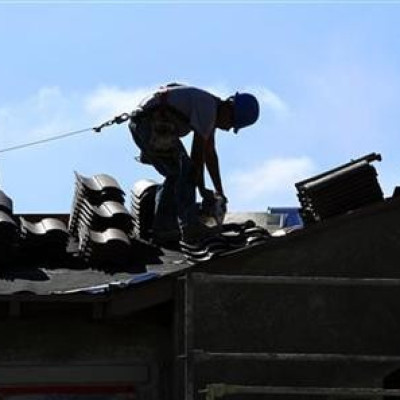 A construction worker cuts tiles as he installs a roof on a home in a new subdivision being built in San Marcos, California