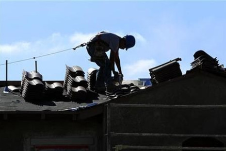 A construction worker cuts tiles as he installs a roof on a home in a new subdivision being built in San Marcos, California