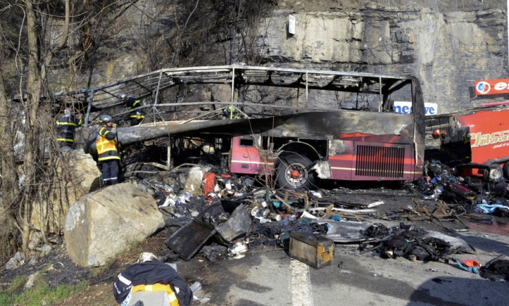 French fire brigade members work around the ruins of a tour bus which crashed and burned on the road from l'Alpe d'Huez in the French Alps (Reuters)