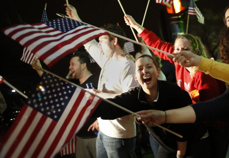 People wave U.S. flags while cheering as police drive down Arlington Street in Watertown, Massachusetts
