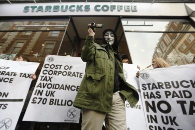 A masked demonstrator leaves a Starbucks outlet in protest against the group's tax practices.