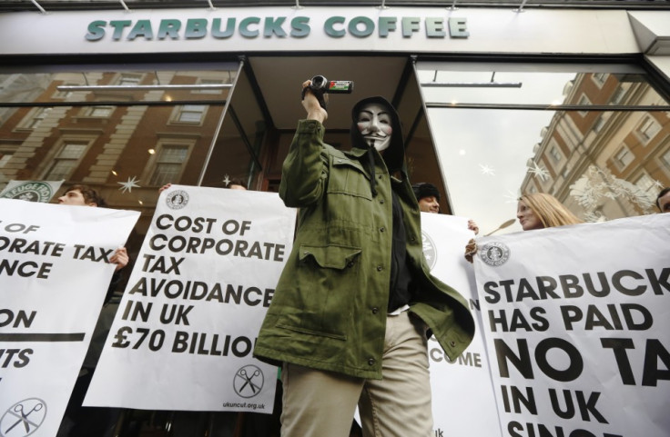 A masked demonstrator leaves a Starbucks outlet in protest against the group's tax practices.
